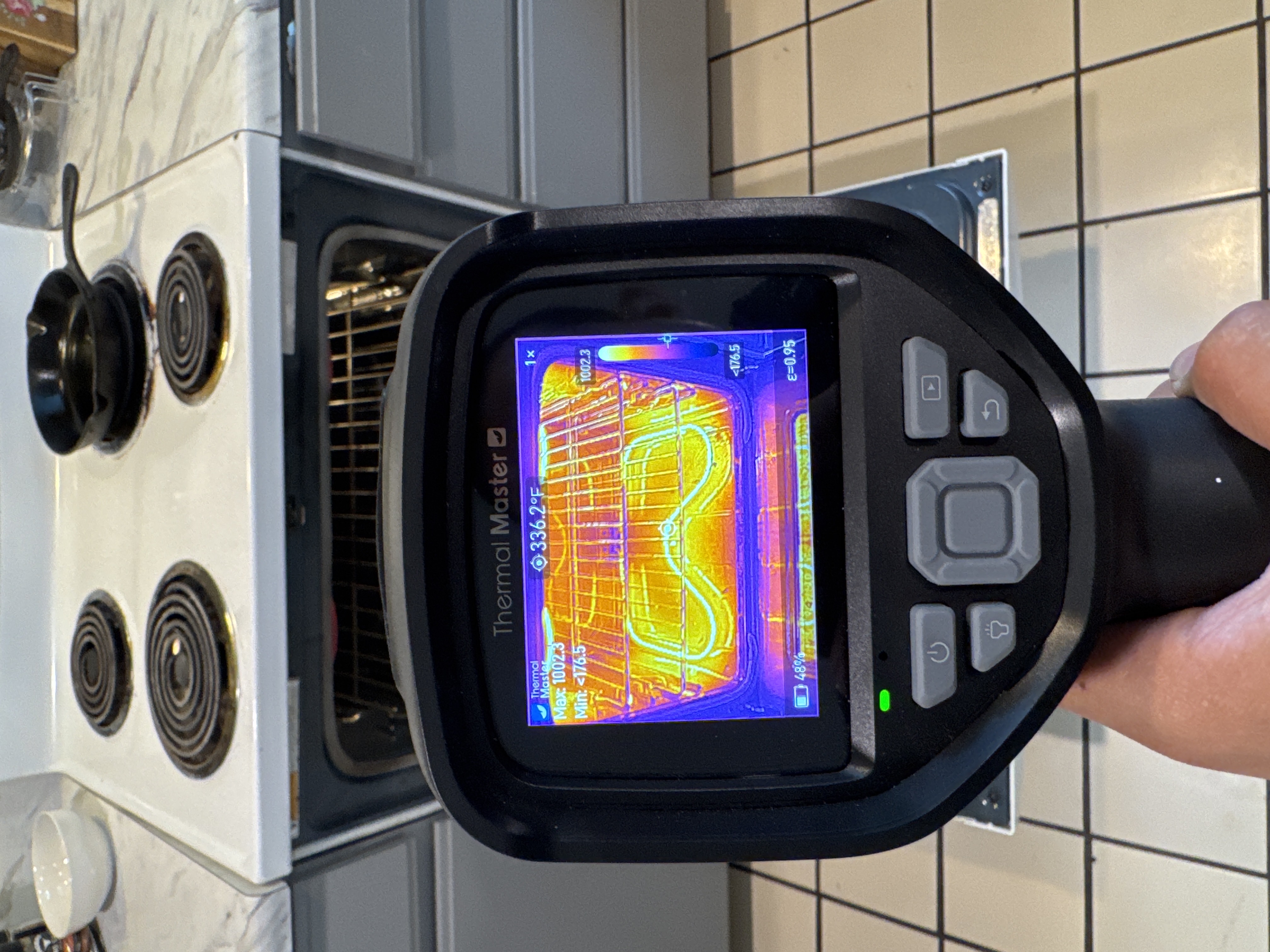 Home inspector using a thermal imaging camera to check an oven during an inspection